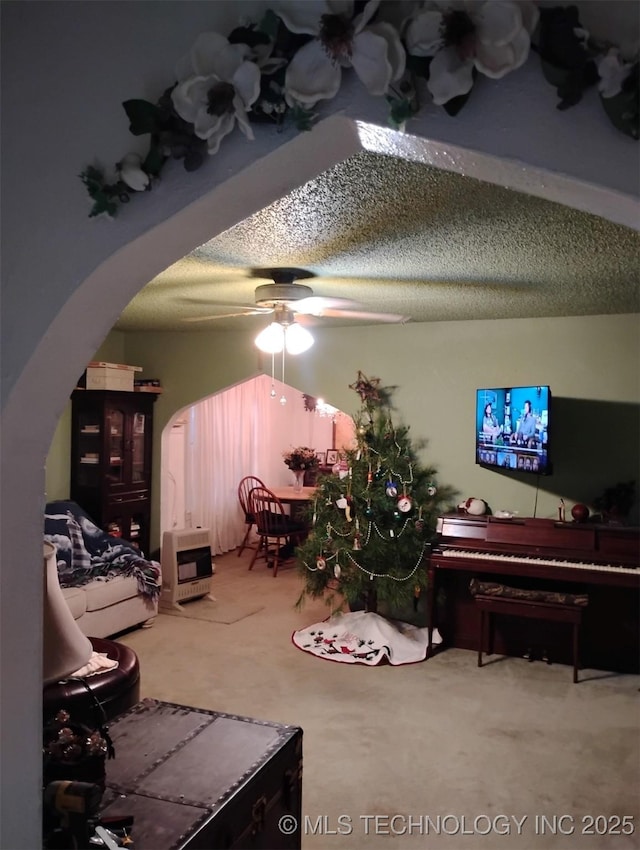 carpeted living room with a textured ceiling, heating unit, and ceiling fan