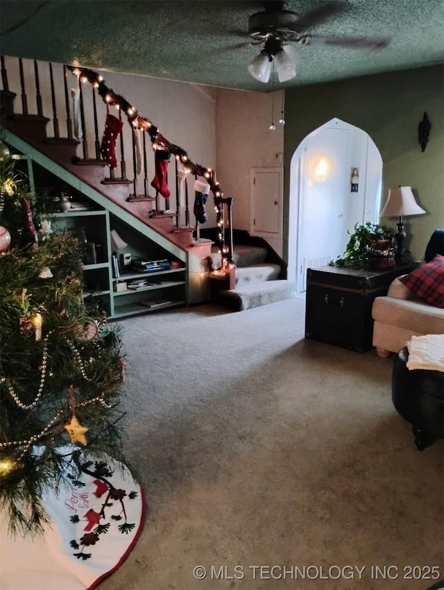 carpeted living room with ceiling fan and a textured ceiling