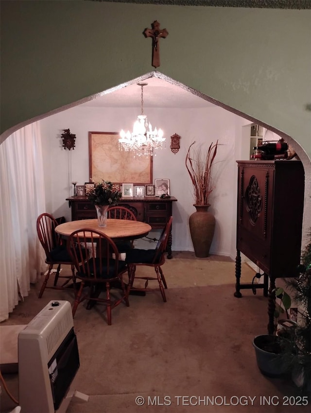 carpeted dining space featuring heating unit and an inviting chandelier