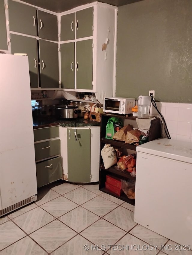 kitchen featuring white fridge, light tile patterned flooring, green cabinets, and fridge