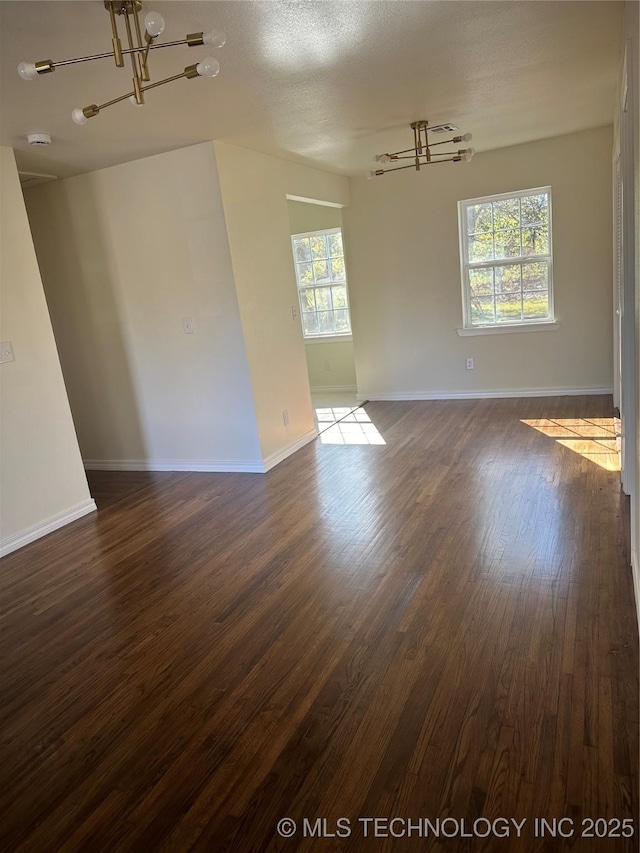 unfurnished room with a healthy amount of sunlight, dark hardwood / wood-style flooring, and a textured ceiling