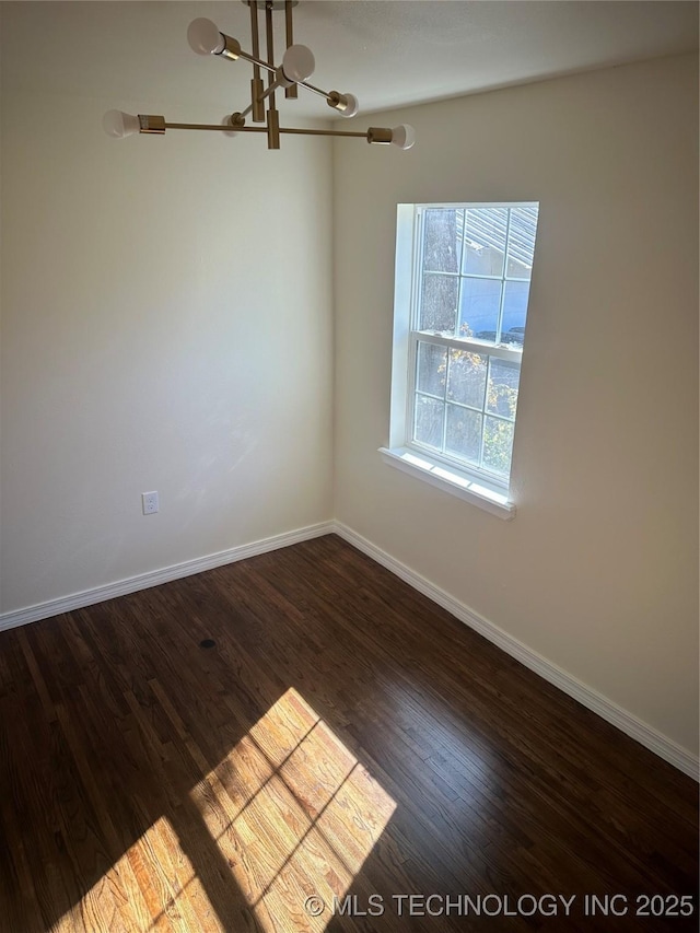 empty room with dark hardwood / wood-style floors and an inviting chandelier