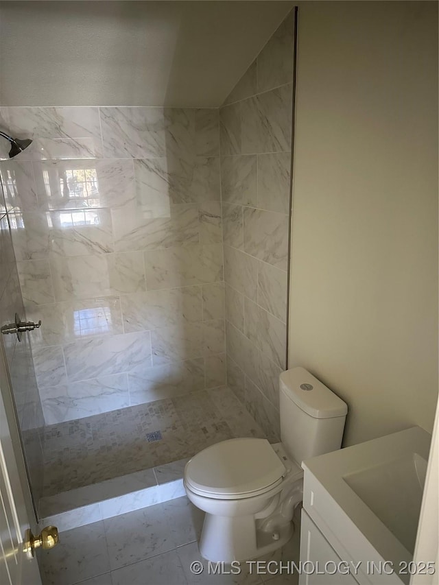 bathroom with a tile shower, vanity, and toilet