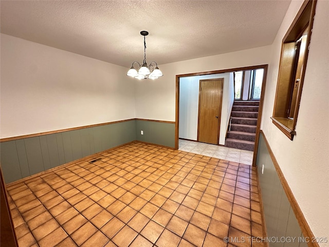 empty room with a chandelier and a textured ceiling