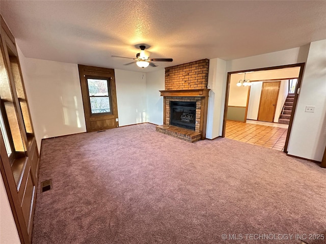 unfurnished living room with ceiling fan with notable chandelier, a fireplace, light colored carpet, and a textured ceiling