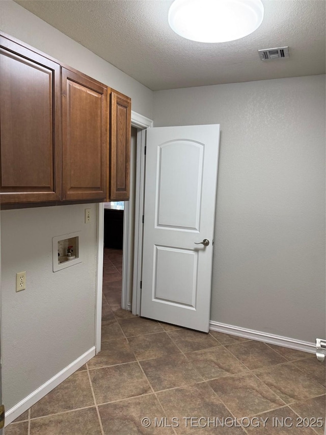 laundry room with cabinets, hookup for a washing machine, and a textured ceiling