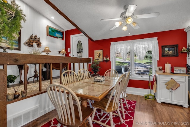 dining space featuring hardwood / wood-style floors, a textured ceiling, vaulted ceiling, and ceiling fan