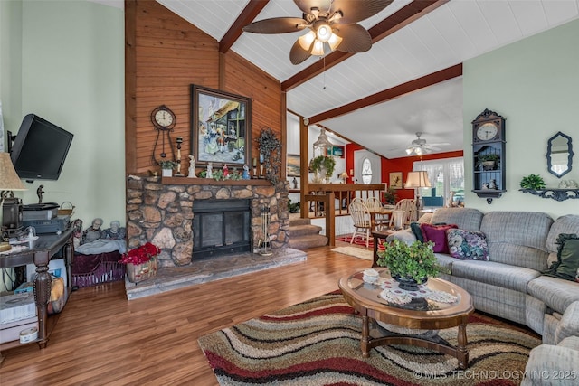 living room featuring high vaulted ceiling, a stone fireplace, hardwood / wood-style flooring, ceiling fan, and beamed ceiling