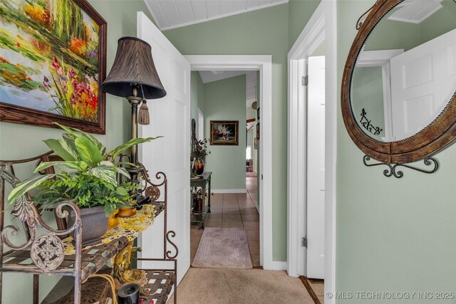 hall featuring light tile patterned floors and vaulted ceiling