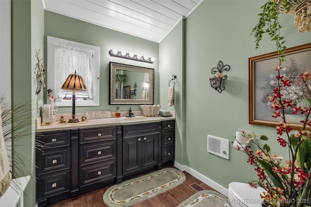 bathroom with vanity, toilet, wood-type flooring, and vaulted ceiling