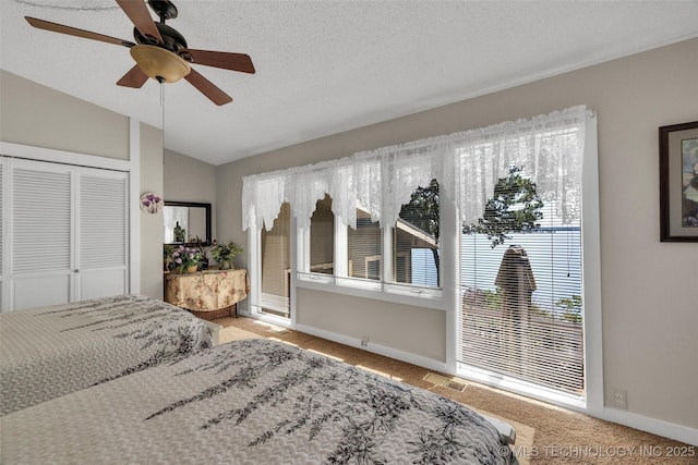 carpeted bedroom with ceiling fan, a closet, a textured ceiling, and vaulted ceiling