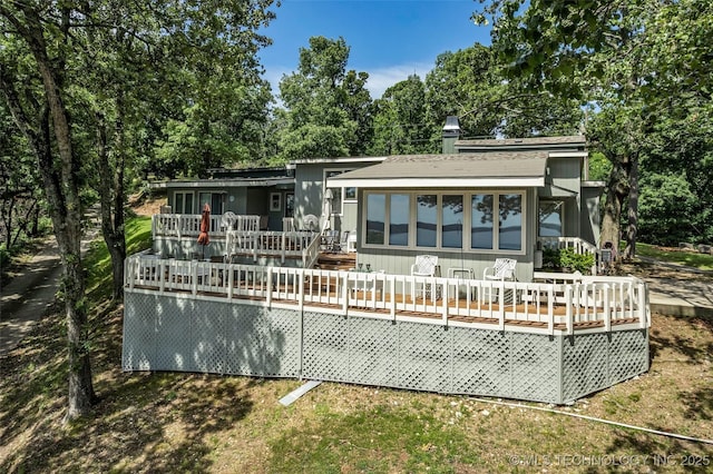 rear view of property featuring a sunroom and a wooden deck