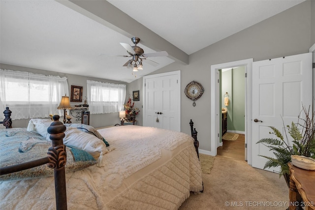 bedroom featuring lofted ceiling with beams, ensuite bath, ceiling fan, light colored carpet, and a closet