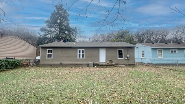 rear view of house featuring central AC unit and a yard