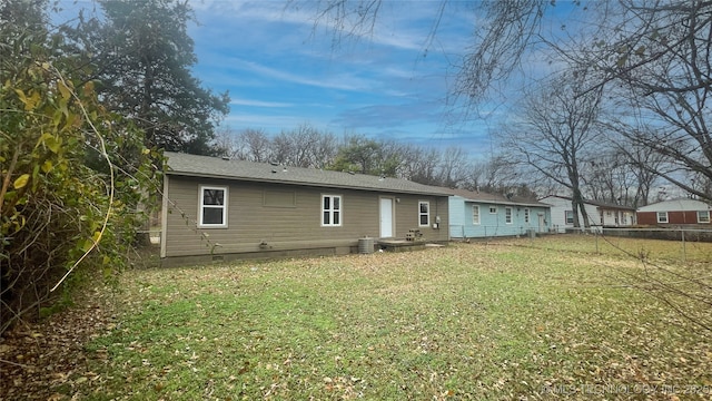 rear view of property with a lawn and central air condition unit