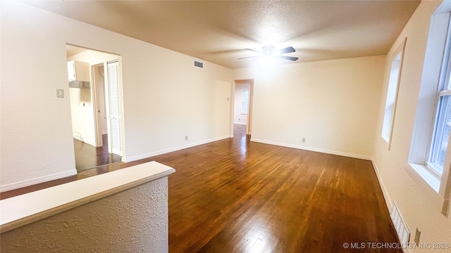 spare room featuring a textured ceiling, ceiling fan, and dark wood-type flooring