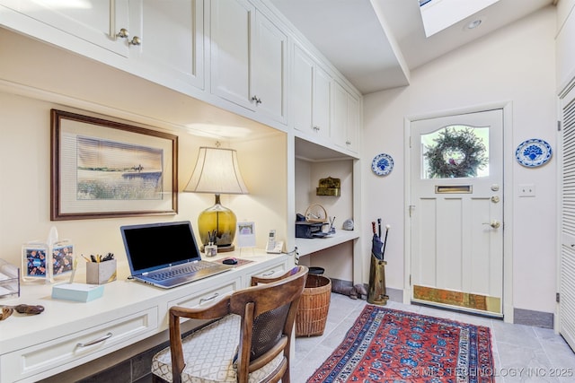 tiled home office featuring vaulted ceiling with skylight and built in desk