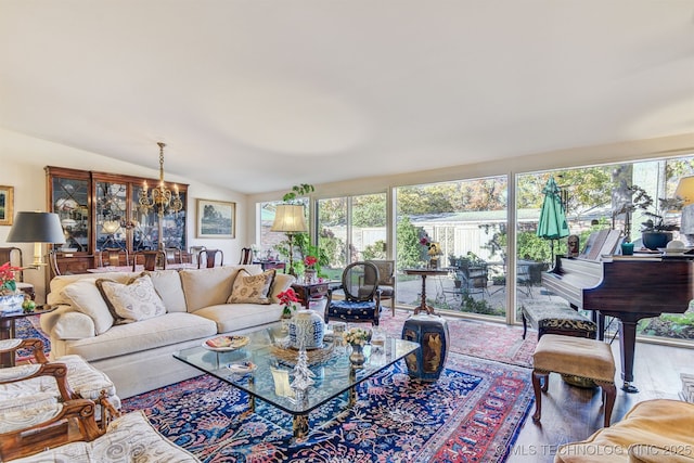 living room featuring hardwood / wood-style flooring, plenty of natural light, lofted ceiling, and an inviting chandelier