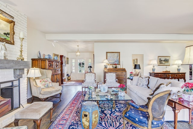 living room with beamed ceiling, hardwood / wood-style floors, and a brick fireplace