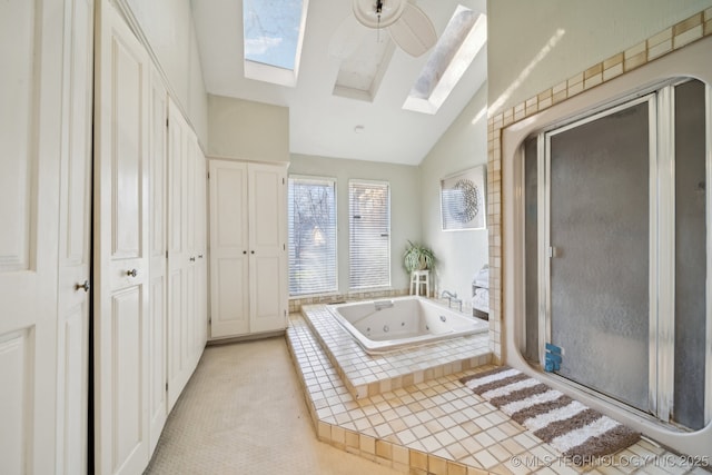 bathroom featuring ceiling fan, independent shower and bath, and vaulted ceiling with skylight