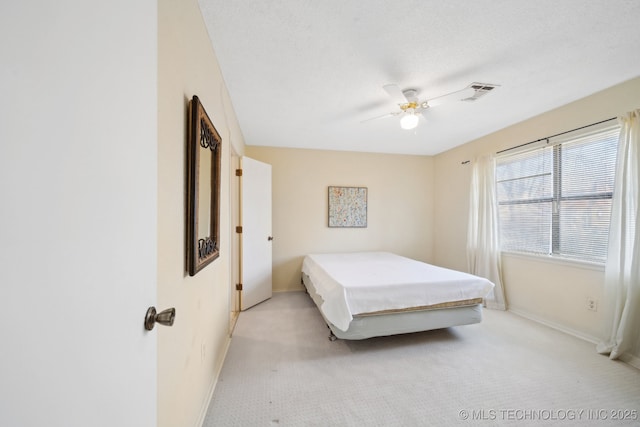 bedroom with ceiling fan, light carpet, and a textured ceiling