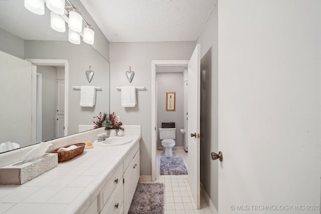 bathroom with tile patterned floors, vanity, toilet, and a textured ceiling