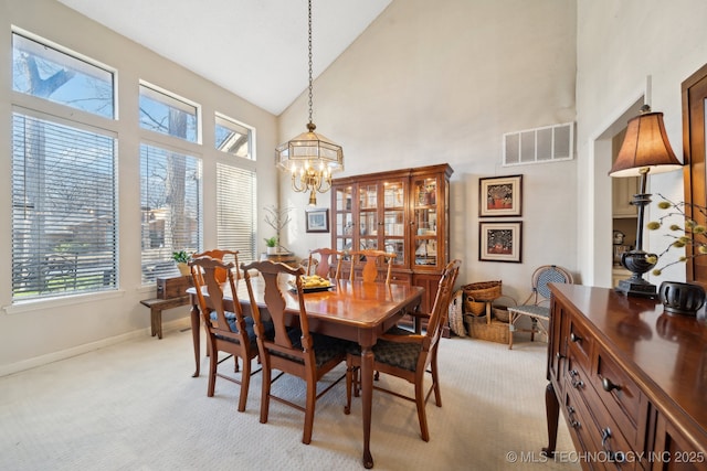 dining area featuring a notable chandelier, light colored carpet, and high vaulted ceiling