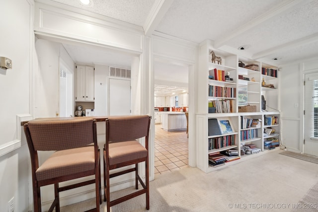 interior space featuring light carpet, a textured ceiling, white cabinetry, and crown molding