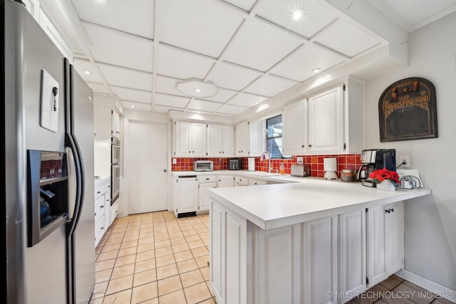 kitchen with backsplash, kitchen peninsula, white cabinets, and stainless steel appliances