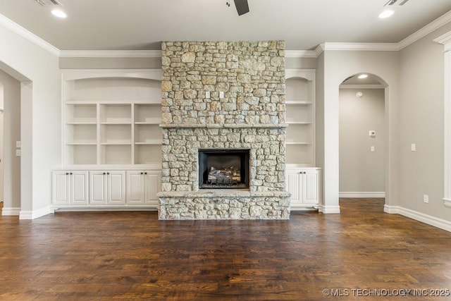 unfurnished living room featuring a fireplace, dark hardwood / wood-style floors, built in features, and crown molding