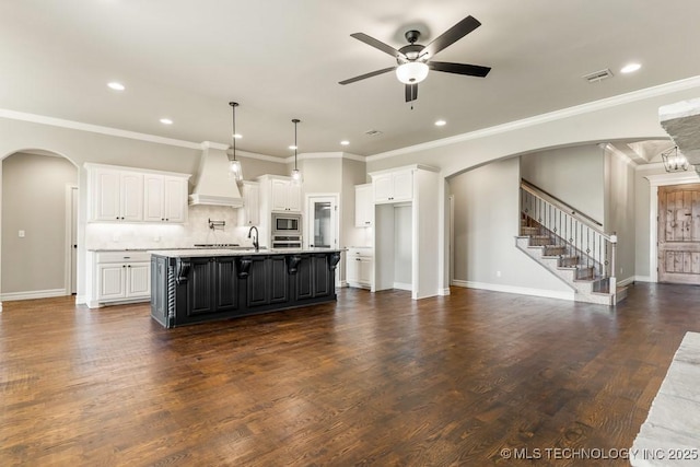 kitchen with white cabinetry, sink, an island with sink, custom exhaust hood, and appliances with stainless steel finishes