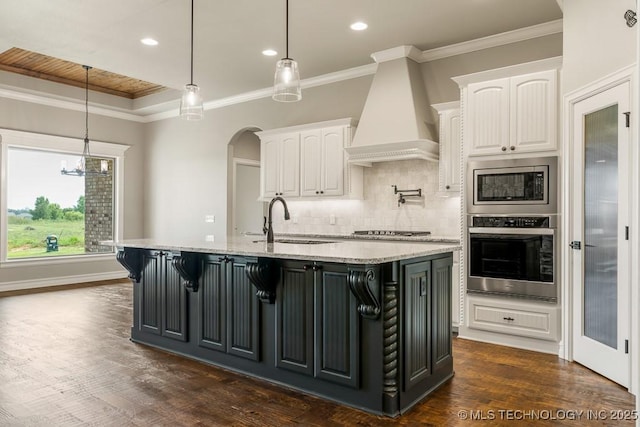 kitchen featuring appliances with stainless steel finishes, white cabinetry, pendant lighting, and custom exhaust hood