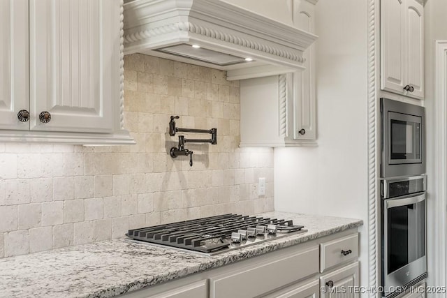 kitchen featuring light stone counters, white cabinetry, appliances with stainless steel finishes, and tasteful backsplash