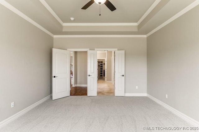 unfurnished bedroom featuring ceiling fan, a raised ceiling, ornamental molding, and light carpet