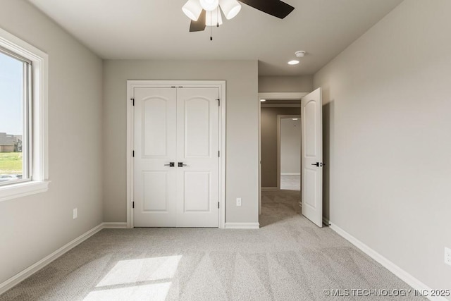 unfurnished bedroom with ceiling fan, light colored carpet, multiple windows, and a closet