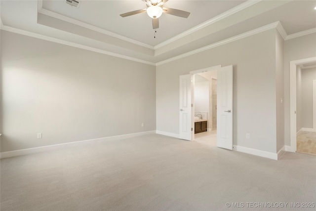 unfurnished bedroom with ensuite bathroom, crown molding, ceiling fan, a tray ceiling, and light colored carpet