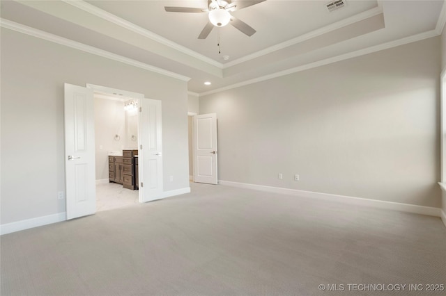 unfurnished bedroom featuring ceiling fan, ensuite bath, crown molding, and a tray ceiling