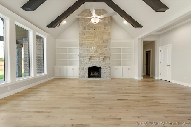 unfurnished living room with ceiling fan, a stone fireplace, built in features, and light hardwood / wood-style flooring