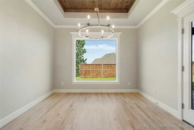 unfurnished dining area with a raised ceiling, ornamental molding, light hardwood / wood-style flooring, and an inviting chandelier