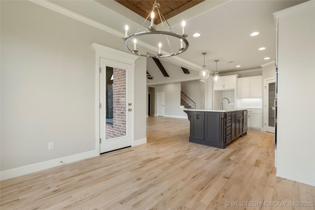 kitchen with white cabinetry, sink, hanging light fixtures, a center island with sink, and light wood-type flooring