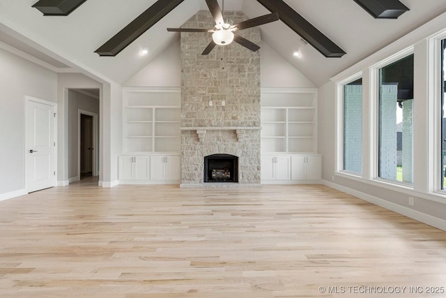 unfurnished living room featuring beamed ceiling, built in shelves, ceiling fan, and a stone fireplace