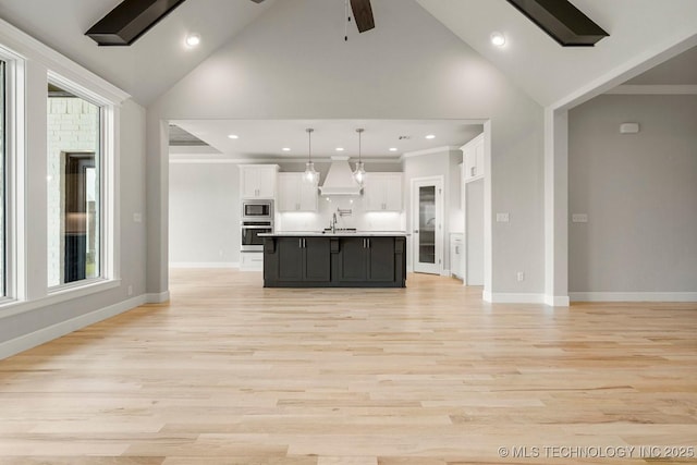 kitchen with pendant lighting, light hardwood / wood-style floors, a kitchen island with sink, white cabinets, and custom range hood