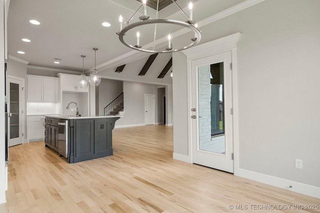 kitchen with sink, hanging light fixtures, a notable chandelier, a kitchen island with sink, and white cabinets