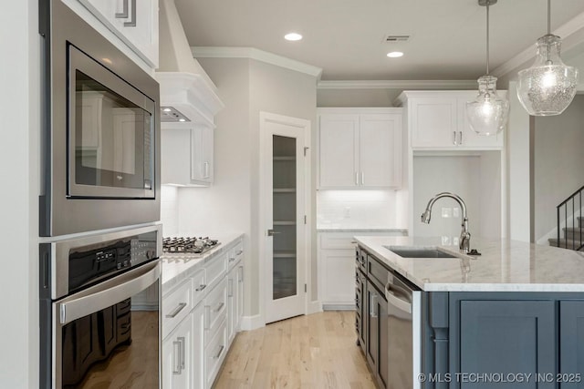 kitchen featuring light stone countertops, appliances with stainless steel finishes, premium range hood, white cabinetry, and hanging light fixtures