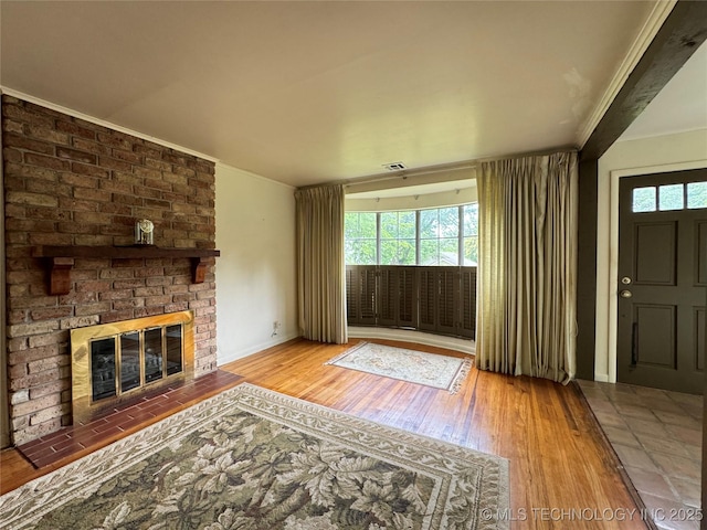 unfurnished living room featuring a brick fireplace, hardwood / wood-style flooring, and ornamental molding