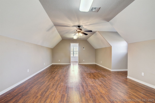 bonus room featuring ceiling fan, lofted ceiling, dark wood-type flooring, and a textured ceiling