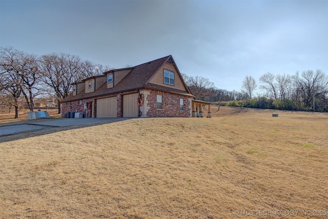 view of side of property with a garage, driveway, brick siding, and a lawn