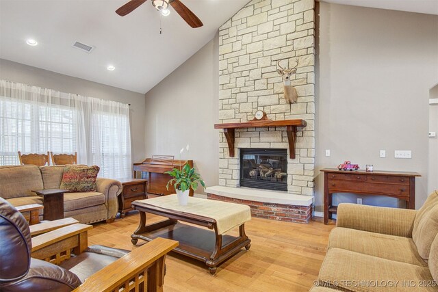 living room with ceiling fan, high vaulted ceiling, a fireplace, and light hardwood / wood-style floors