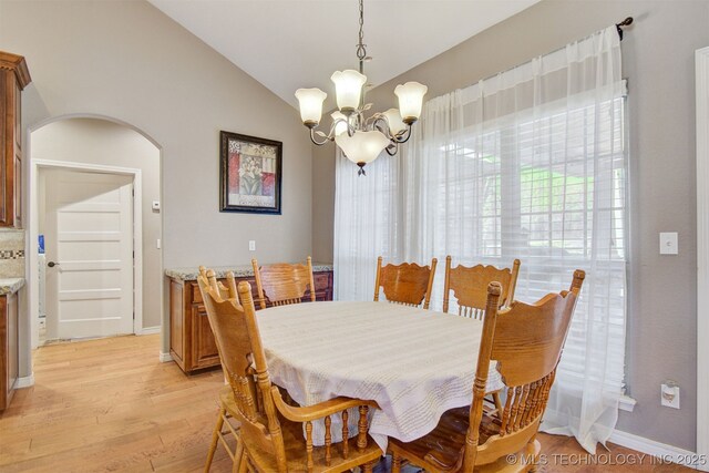 dining room featuring lofted ceiling, a chandelier, and light hardwood / wood-style floors