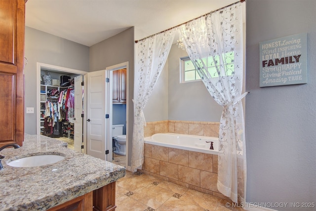 bathroom featuring tile patterned floors, vanity, toilet, and tiled tub